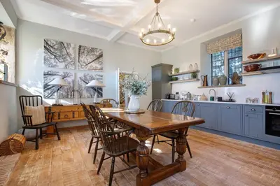 a kitchen with a wooden table and chairs and a dining room at Gatehouse East in Saint Osyth