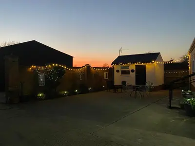 a backyard with a fence and a house with lights at Paddock View - Snetterton Norfolk in Norwich