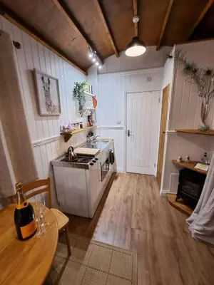 a kitchen with a stove and a sink and a table at Back in Thyme in Colchester