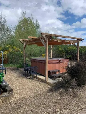 a wooden pergola with a bench and a table at Back in Thyme in Colchester