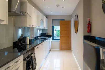 a kitchen with white cabinets and black counter tops at Beautiful 2 Bedroom Home in Cambridge
