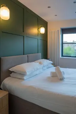 a bedroom with a bed with white sheets and a window at Beautiful 2 Bedroom Home in Cambridge