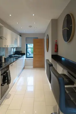 a large kitchen with white cabinets and blue chairs at Beautiful 2 Bedroom Home in Cambridge