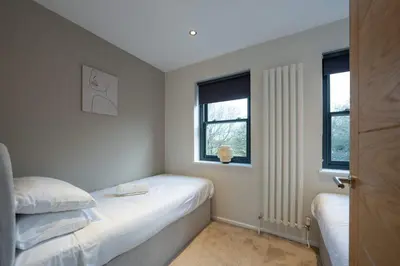 a small bedroom with two beds and two windows at Beautiful 2 Bedroom Home in Cambridge