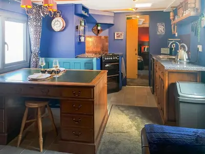 a kitchen with blue walls and a wooden island with a counter at The Fox - Uk48554 in Colchester