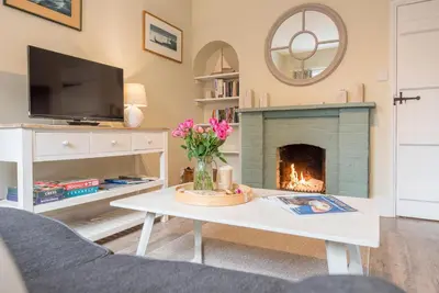 a living room with a fireplace and a tv at Castle Cottage, Orford in Orford