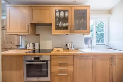 a kitchen with wooden cabinets and a sink at Castle Cottage, Orford in Orford