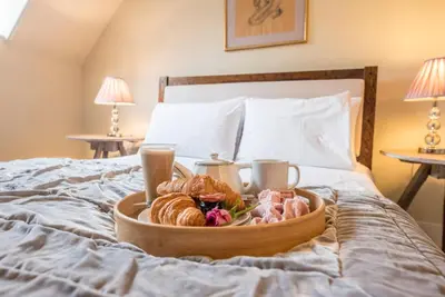 a tray of pastries and croissants on a bed at Castle Cottage, Orford in Orford