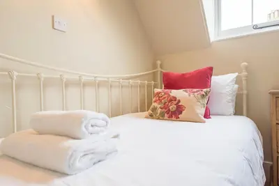 a bedroom with a white bed with towels on it at Castle Cottage, Orford in Orford