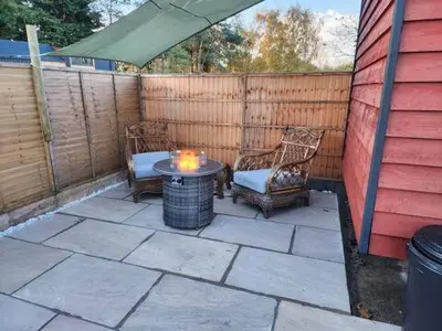 a patio with two chairs and a table and a fence at M Lodge in Colchester
