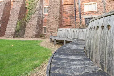 a wooden walkway with a bench in front of a building at Kiln House, Snape Maltings in Snape