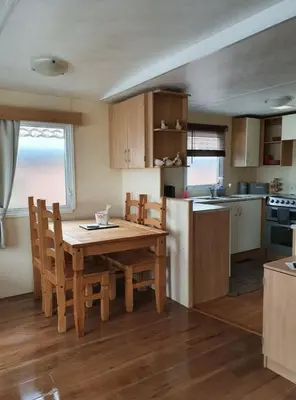 a kitchen with a wooden table and chairs and a kitchen with a refrigerator at The Duckhouse in Great Horkesley