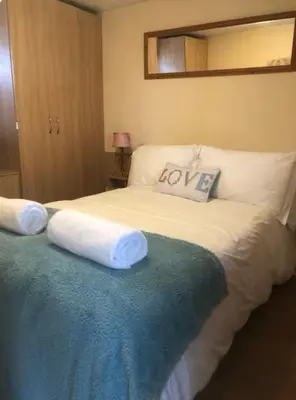 a bedroom with a bed with white sheets and a mirror at The Duckhouse in Great Horkesley