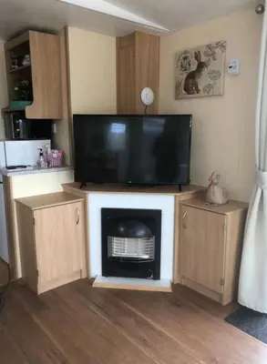 a living room with a flat screen tv on a entertainment center at The Duckhouse in Great Horkesley