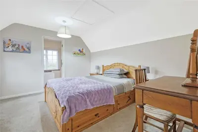 a bedroom with a wooden bed and a desk at Blackbrook Farmhouse with free off-street parking for 10 cars in Colchester