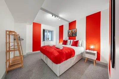 a red and white bedroom with a bed and a ladder at The Jockey Suite-Newmarket High Street-Two Double Bedroom Apartment in Newmarket