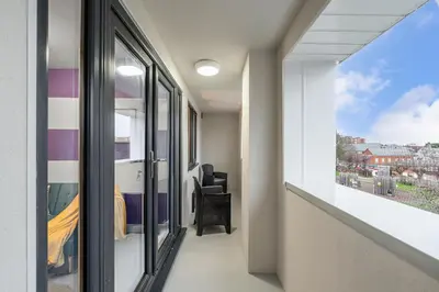 a room with a balcony with a view of a city at The Jockey Suite-Newmarket High Street-Two Double Bedroom Apartment in Newmarket