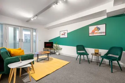 a living room with green chairs and a tv at The Jockey Suite-Newmarket High Street-Two Double Bedroom Apartment in Newmarket