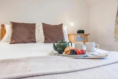 a breakfast tray with a tea set on a bed at Ann Page Cottage, Aldeburgh in Aldeburgh