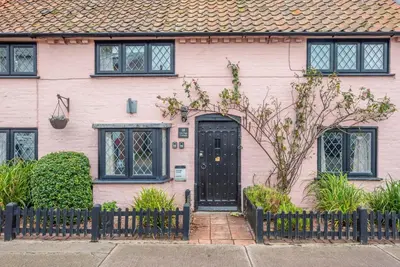 a pink house with a black door at Ann Page Cottage, Aldeburgh in Aldeburgh