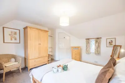 a bedroom with a white bed and a chair at Ann Page Cottage, Aldeburgh in Aldeburgh
