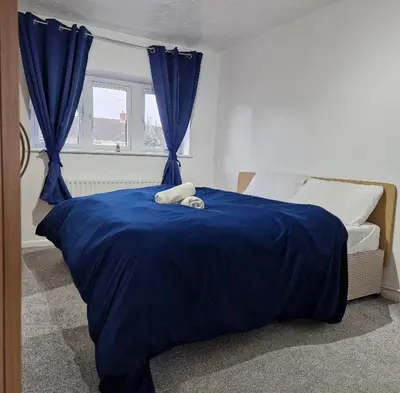 a bedroom with a blue bed with blue sheets and a window at Cosy large double room in Basildon