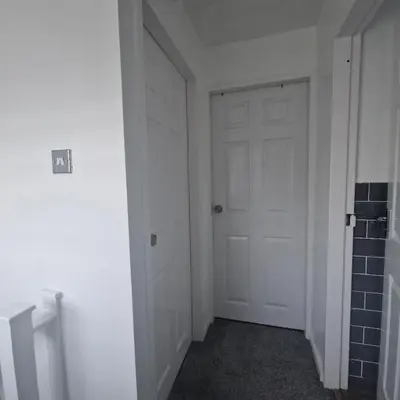 an empty hallway with a white door and a wall at Cosy large double room in Basildon