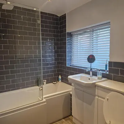 a bathroom with a sink and a tub and a toilet at Cosy large double room in Basildon