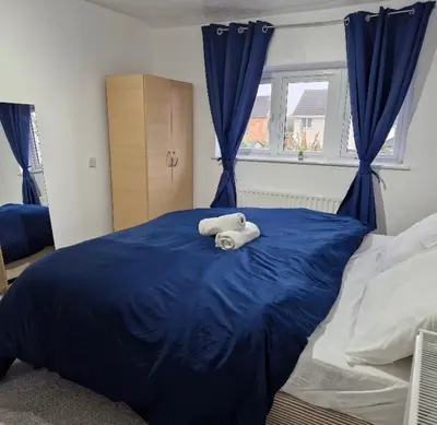 a bedroom with a blue bed with towels on it at Cosy large double room in Basildon
