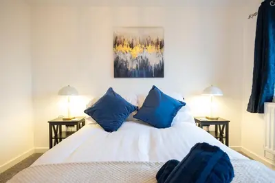 a bedroom with a white bed with blue pillows at Kingfisher in Haverhill