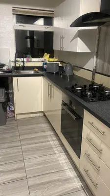 a kitchen with white cabinets and a black counter top at The Comfort Suite in Havering atte Bower