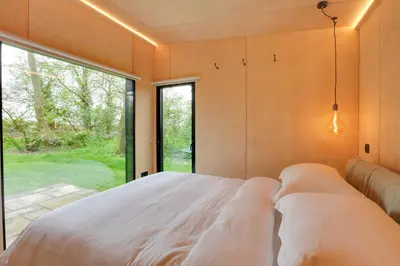a bedroom with a bed and a large window at The Woods - Luxury cabin in a woodland setting in Hatfield Broad Oak