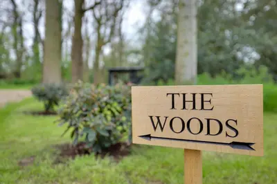 a sign that reads the woods in a park at The Woods - Luxury cabin in a woodland setting in Hatfield Broad Oak