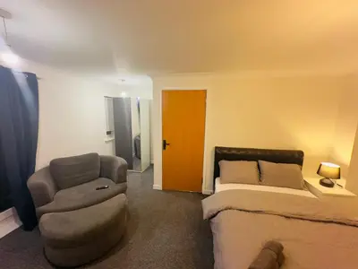 a bedroom with a bed and a chair and a door at Comfortable Double Rooms in a Beautiful House in Ipswich