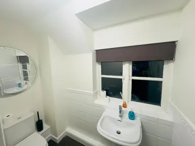 a white bathroom with a sink and a window at Comfortable Double Rooms in a Beautiful House in Ipswich