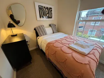 a bedroom with a bed and a mirror and a window at Grange Luxe 4 in Martlesham Heath