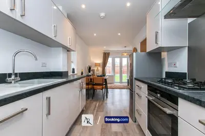 a kitchen with white cabinets and black counter tops at Charming 2 BDR House By AR Properties Short Lets & Serviced Accommodation Colchester in Colchester