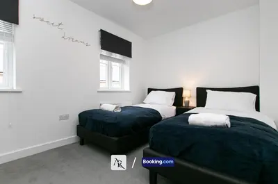 a bedroom with two beds and a stairway at Charming 2 BDR House By AR Properties Short Lets & Serviced Accommodation Colchester in Colchester