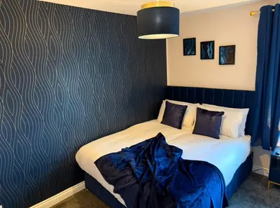 a bedroom with a bed with a blue accent wall at Newly decorated Cozy home! in Hythe