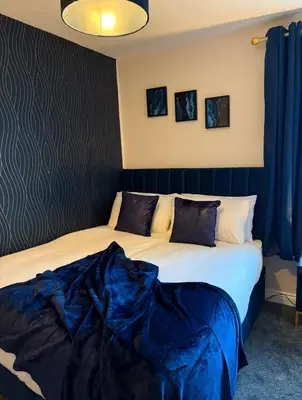 two beds in a room with blue drapes at Newly decorated Cozy home! in Hythe