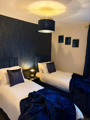 a hotel room with two beds with blue sheets at Newly decorated Cozy home! in Hythe