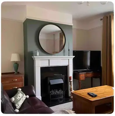 a living room with a mirror over a fireplace at Tardis Vibes in Stowmarket