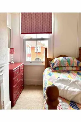a bedroom with a bed with a dresser and a window at Tardis Vibes in Stowmarket