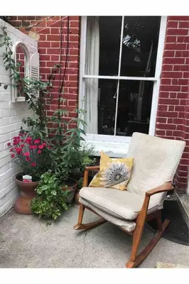 a chair sitting on a porch in front of a window at Tardis Vibes in Stowmarket
