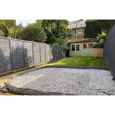 a backyard with a fence and a gravel driveway at Tardis Vibes in Stowmarket