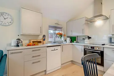 a kitchen with white cabinets and a clock on the wall at 2 Bed in Wickhambrook oc-b30507 in Wickhambrook