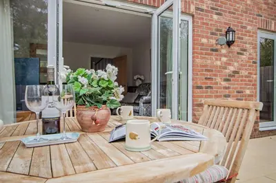 a wooden table with wine glasses and a vase of flowers at 3 Bed in Framlingham oc-f30353 in Framlingham
