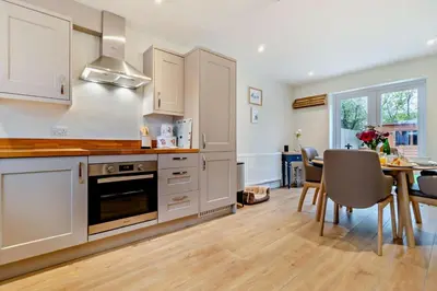 a kitchen with white cabinets and a table and a dining room at 3 Bed in Framlingham oc-f30353 in Framlingham