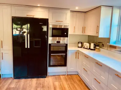 a black refrigerator in a kitchen with white cabinets at The Old Coach House in Hockwold cum Wilton