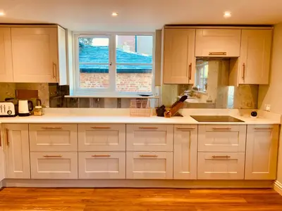 a kitchen with white cabinets and a sink and a window at The Old Coach House in Hockwold cum Wilton